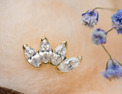 Bijou doré serti de cristaux, posé sur tissu duveteux avec fleurs bleues